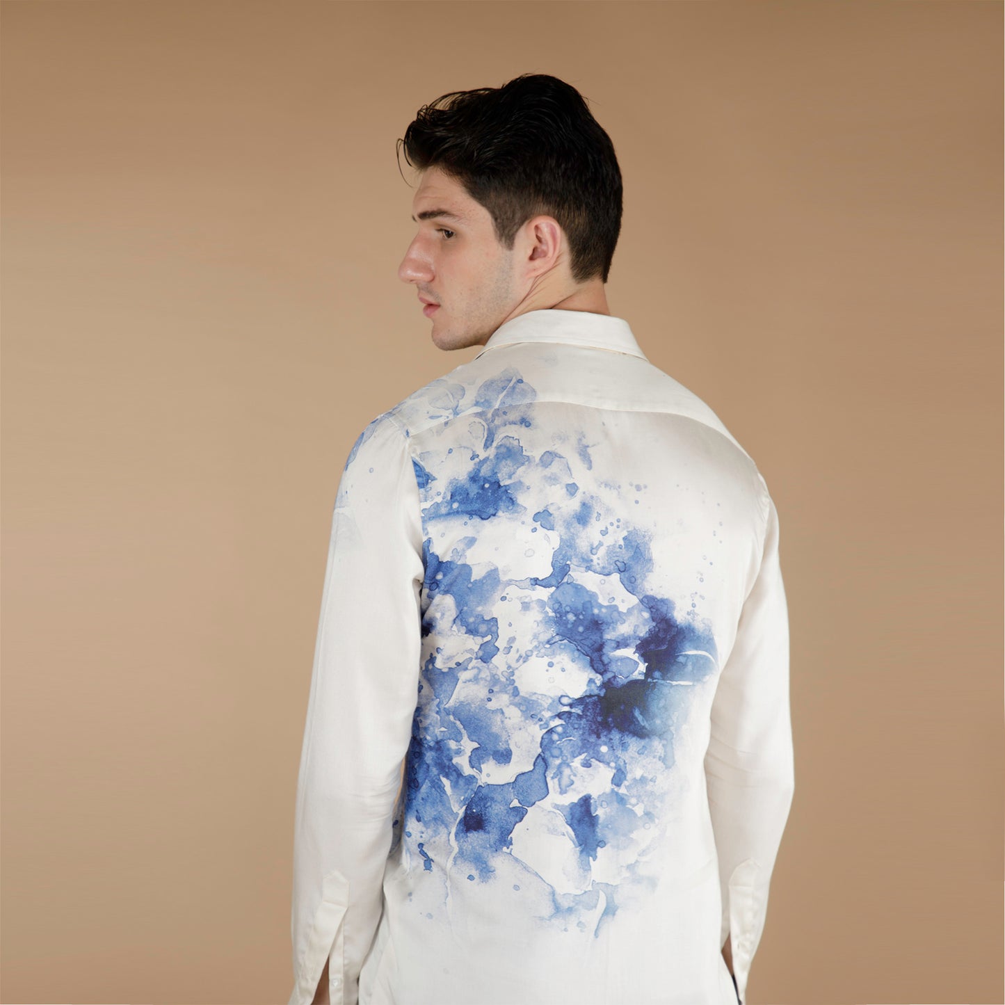 Global medium size model wearing an exquisite Cream and Blue printed organic lotus fabric shirt, meticulously crafted from luxurious Lotus stem silk fabric. Adorned with a striking blue floral in front and back with a placement print cascading from the left side to the right, against a pristine cream base