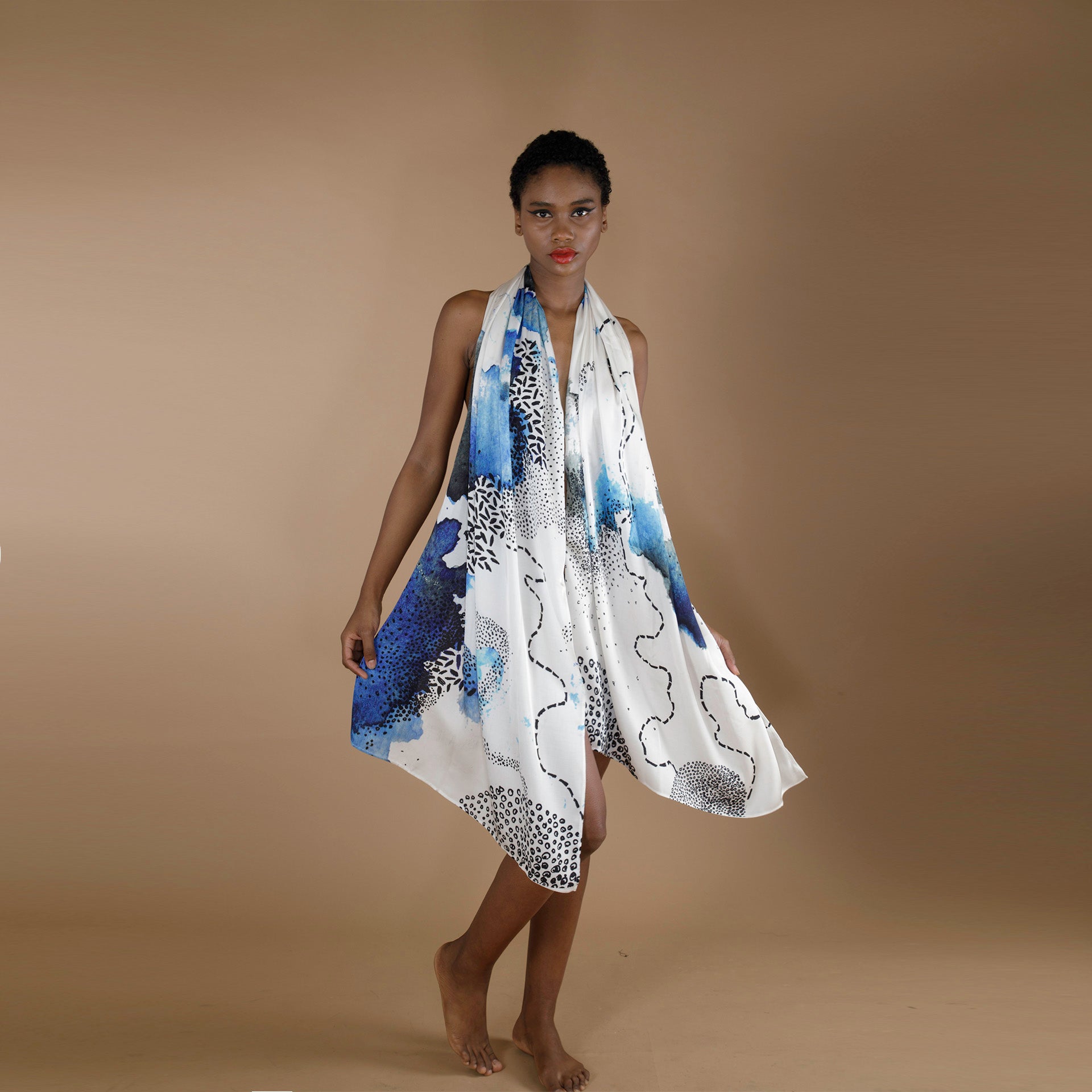 A Global small size model draped in a printed organic rose petal silk fabric. The scarf is printed on a white base with blue and black print inspired from our botanical geometry collection.