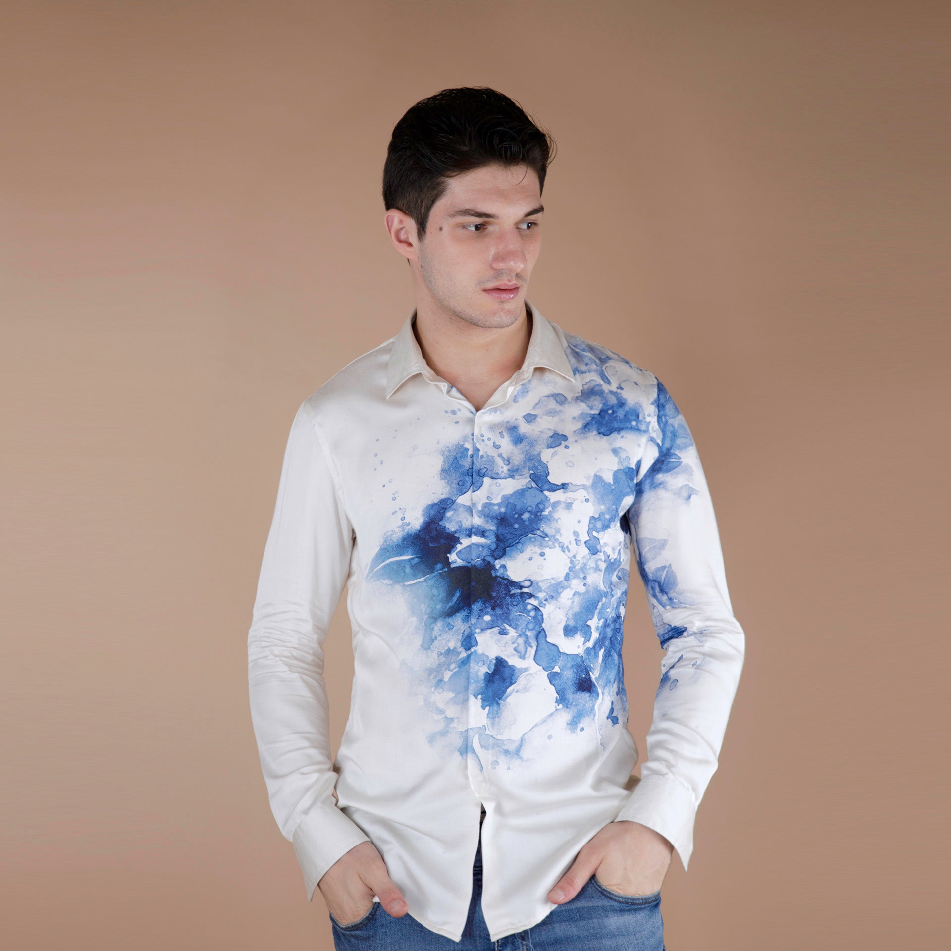Global medium size model wearing an exquisite Cream and Blue printed organic lotus fabric shirt, meticulously crafted from luxurious Lotus stem silk fabric. Adorned with a striking blue floral in front and back with a placement print cascading from the left side to the right, against a pristine cream base