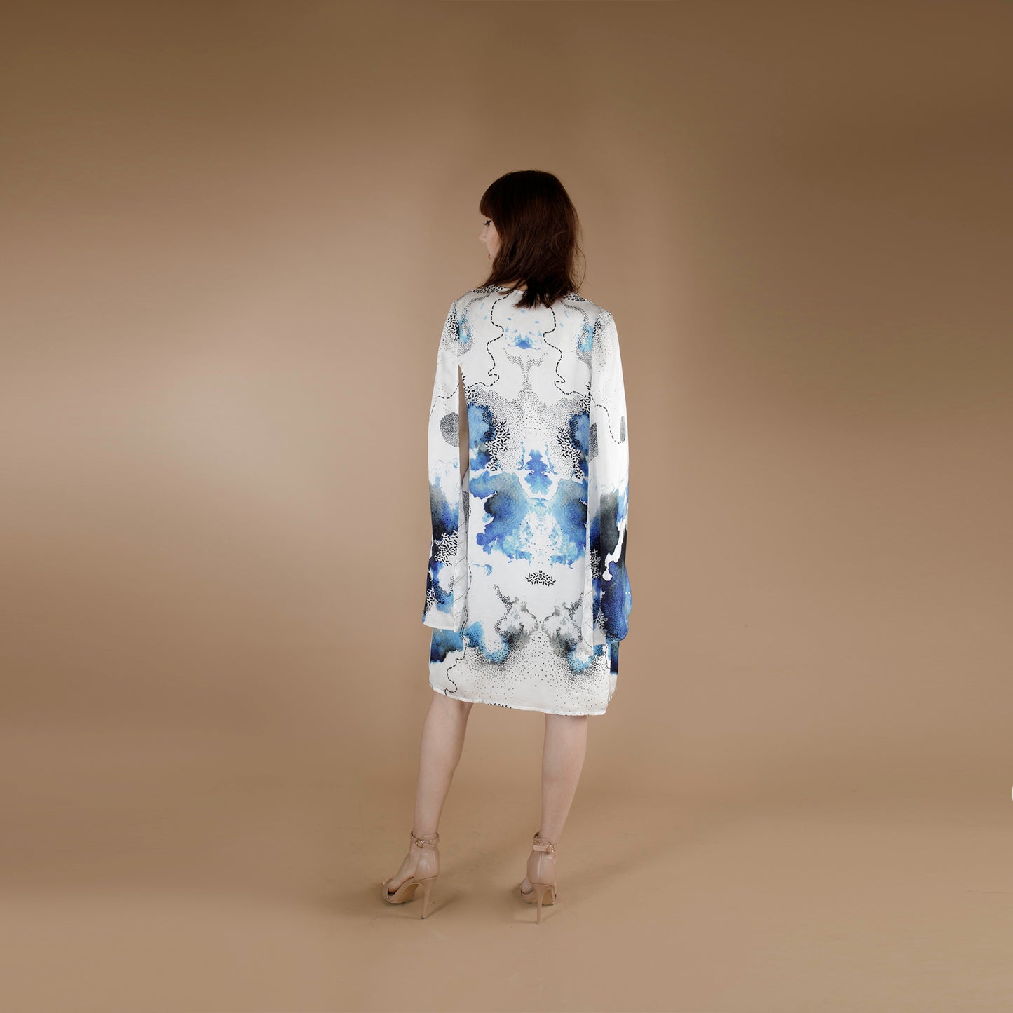 Global Small size model wearing a knee length printed cape paired with solid blue tube dress crafted in Organic Lotus Stem fabric, printed and dyed with non toxic GOTS certified inks.