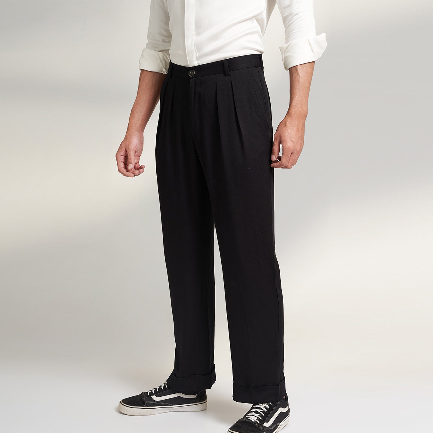 A global medium size model wearing BLACK ORGANIC LOTUS SILK FABRIC TROUSERS. the trouser has a straight comfort fit with turn up bottom and 2 front pleats from house of Parvi.
