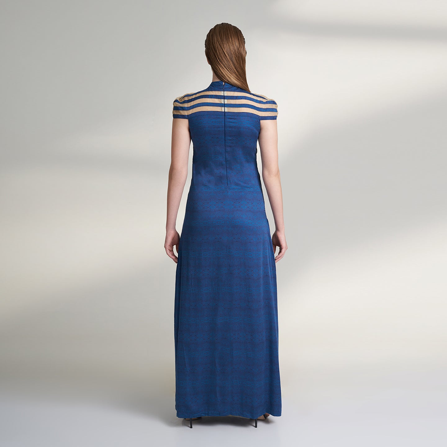 A printed blue long evening dress crafted in organic lotus silk and organza fabric accentuated with a thigh high slit and a short stripe cape attached to the dress.