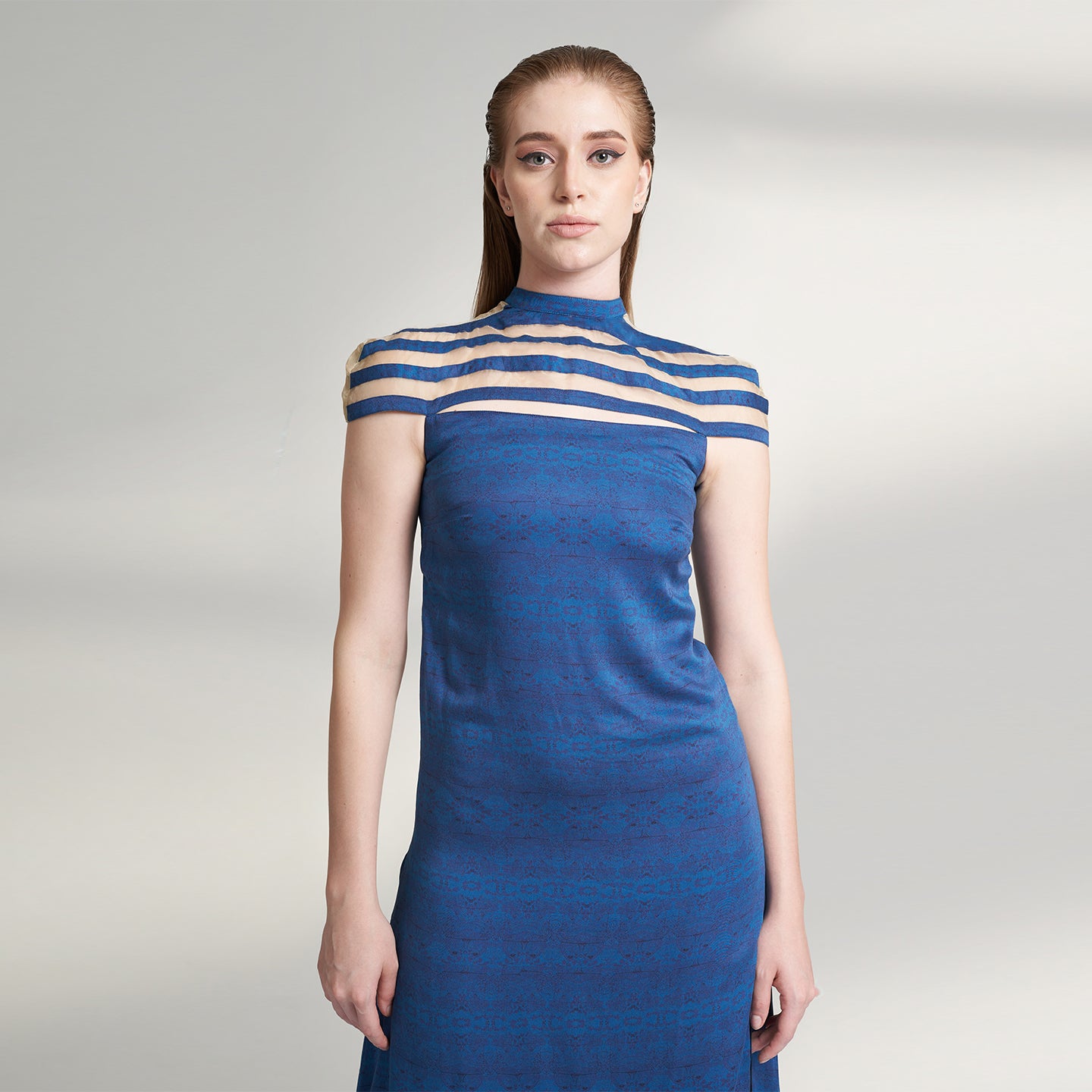 A printed blue long evening dress crafted in organic lotus silk and organza fabric accentuated with a thigh high slit and a short stripe cape attached to the dress.