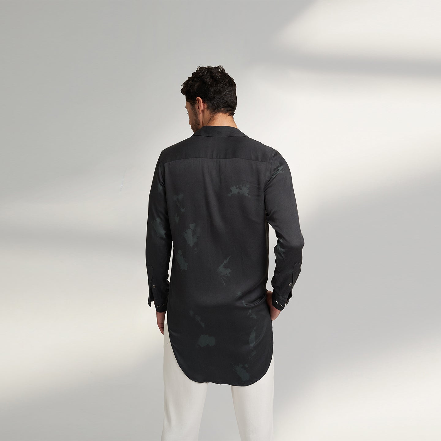back of a man wearing a black shirt and white pants
