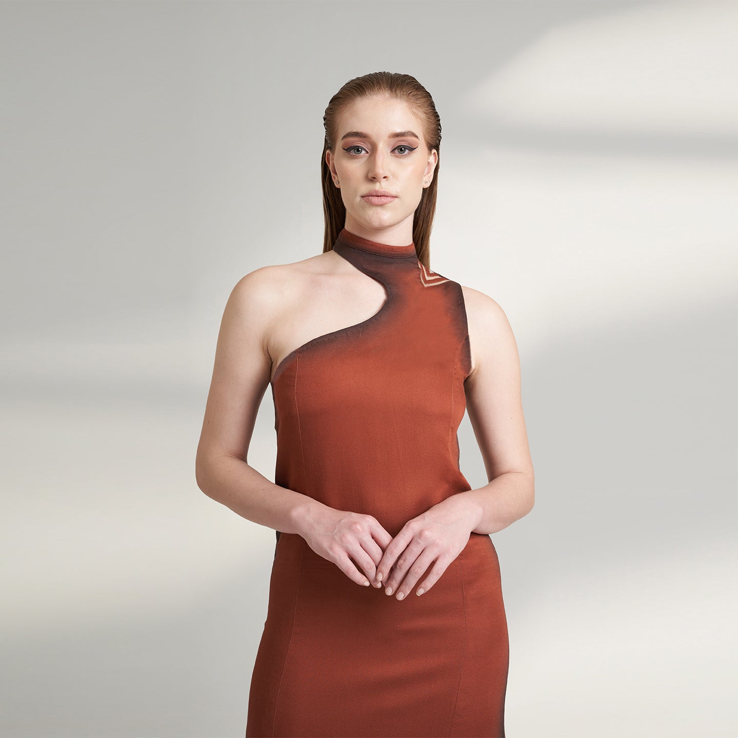 A global medium size model wearing a maroon wine dress with an asymmetrical neckline and a cut-work on left shoulder highlighted with ombre edges all over; crafted in organic lotus stem fabric.